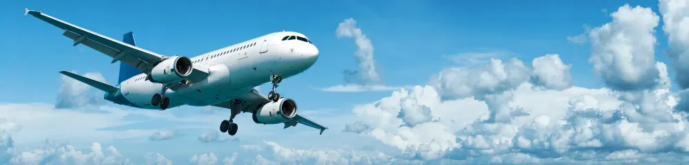 Airplane flying through a blue sky with white clouds